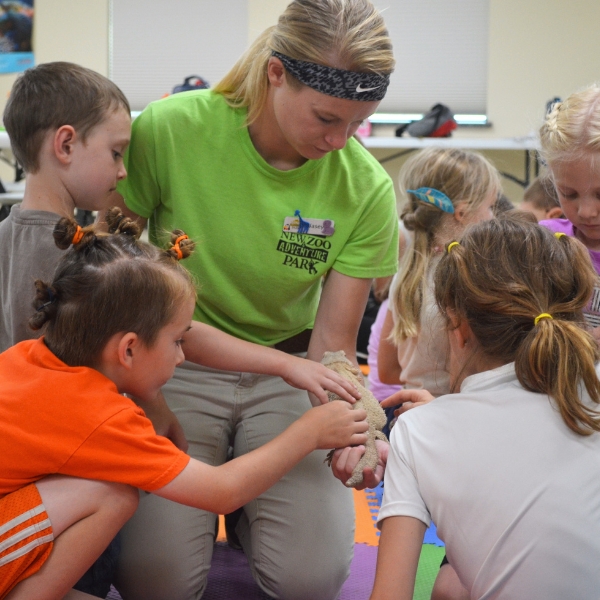 Children touching lizard, gathered around intern holding it