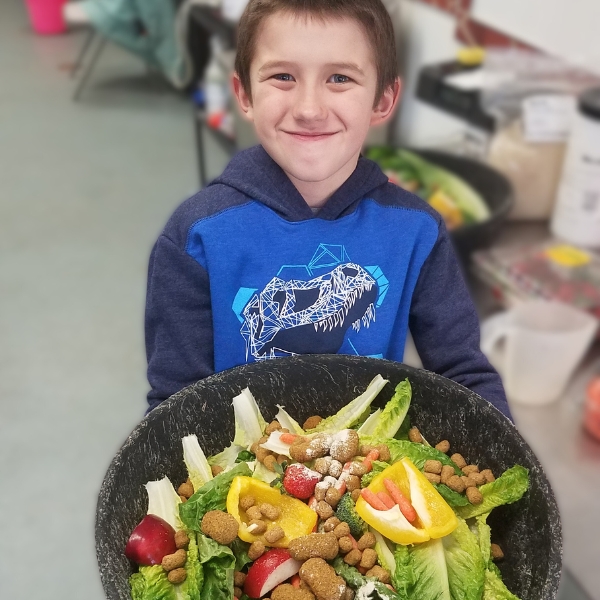 Smiling boy holds bowl of animal food