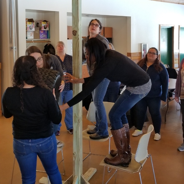 People stand on chairs while playing team building game