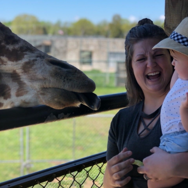 Smiling mother and child feed a giraffe