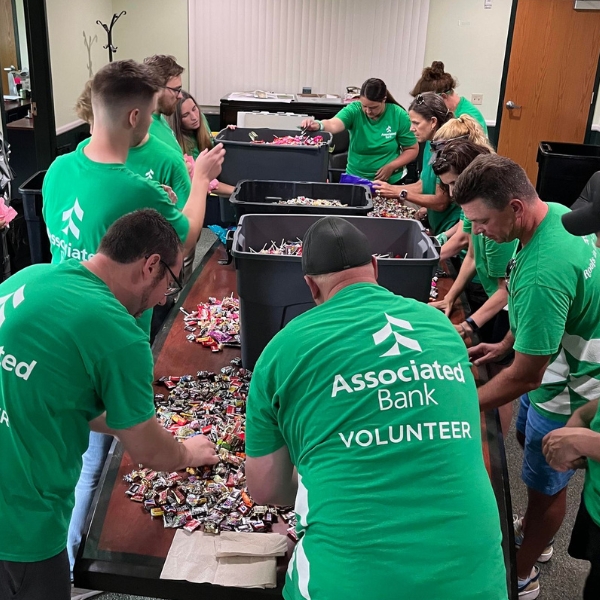 Group of volunteers sort candy while standing around a large table