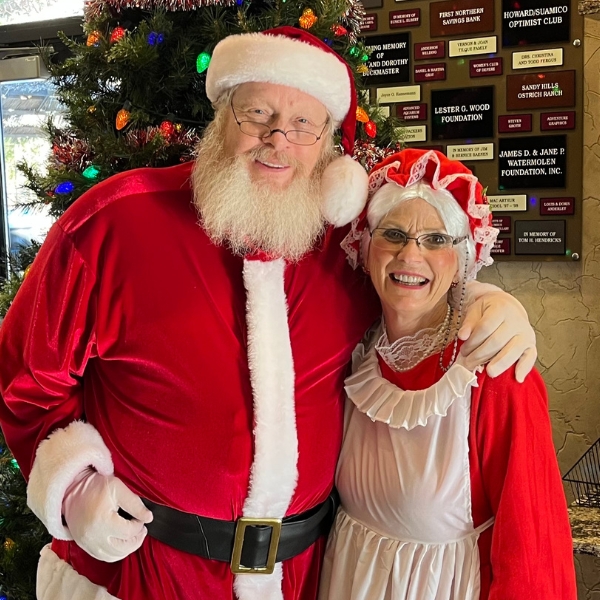 Volunteer dressed as Mrs. Claus smiles with Santa