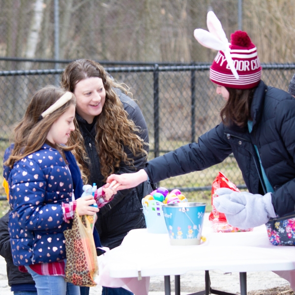 Volunteer wearing bunny ears hands candy to guests