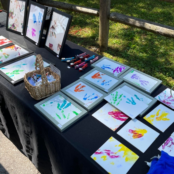 A table is filled with colorful canvas boards covered in penguin footprints made with paint.