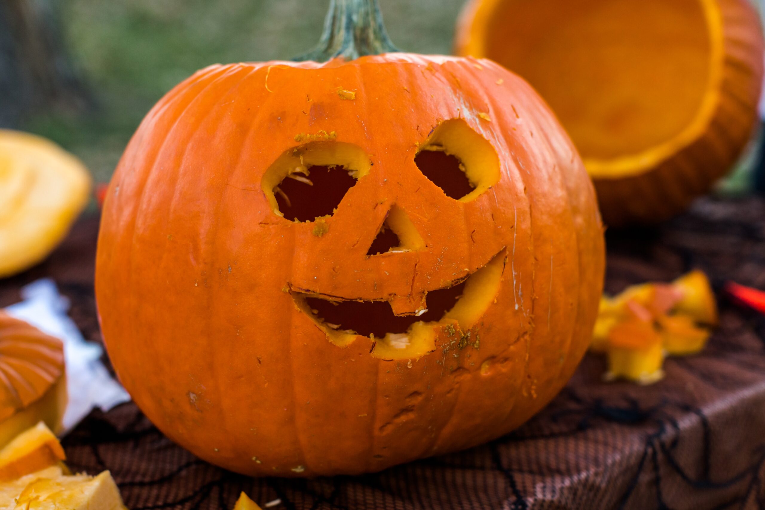 A pumpkin with carved eyes, nose, and a smiling face sits on a table.